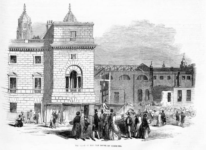 A black and white sketch of the temporary House of Commons being demolished. To the left of the picture is a three story brick building with a flat roof. In the foreground is a group of people onlooking the demolition, with men in top hats and women in frocks. Next to the the building to the left but just in the background is the temporary house of commons, noticeable by its temporary textured outside. The roof has been removed. 