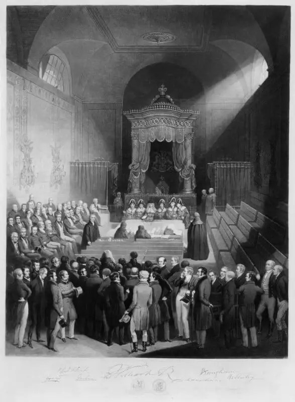 A black and white painting of the House of Lords chamber while the Reform Bill is receiving the King's Assent by Royal Commission. In the middle of the picture at the back is the Throne of Great Britain, which is unoccupied. Six men are sitting in front of the throne next to the woolsack, wearing robes and bicorne hats. The House is full of peers, all sitting either on the left side, on the benches of pro-reform peers, or standing next to these benches. To the right the benches of the anti-reform peers are empty. 