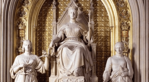 A statue of a queen on a throne with two women to either side